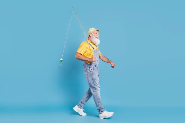 Adatlap side photo of aged man happy positive smile go walk fisherman spinning rod isolated over blue color background — Stock Fotó