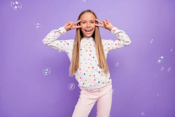 Fotografie přátelské malé dámy mýdlo bublina fly show V-sign oblečení tečkované pyžama izolované fialové barvy pozadí — Stock fotografie