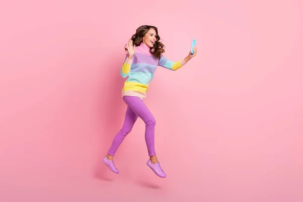 Full body profil boční fotografie mladé dívky chůze skok vlna hi mluvit video smartphone izolované přes pastelové barvy pozadí — Stock fotografie