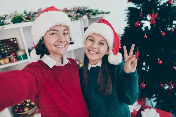 Photo of two blogger kids take x-mas family portrait girl show v-sign wear jumper hat in decorated home indoors — Stock Photo, Image