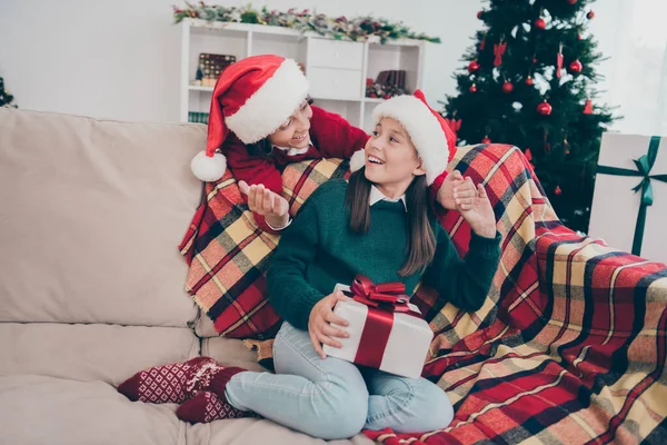 Photo of funny positive children exchange surprise presents wear x-mas hat jumper in decorated home indoors — Stock Photo, Image