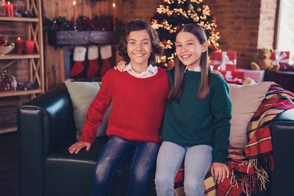 Porträtt av två attraktiva glada syskon tillbringar nyår festlig tid dag sitter på divan kramar på loft hem inomhus — Stockfoto