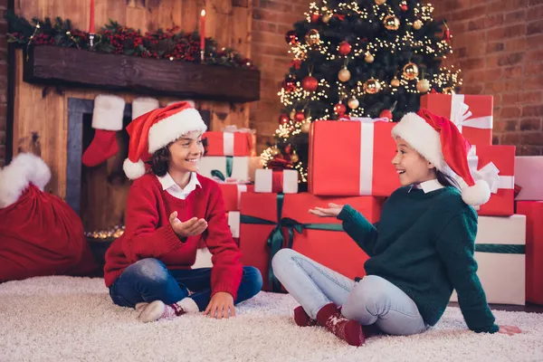 Porträt attraktiver, fröhlicher Geschwister, die die festliche Zeit des neuen Jahres verbringen, Weihnachtsmann-Helfer stapeln Geschenkkartons in dekorierten Loft-Innenräumen — Stockfoto
