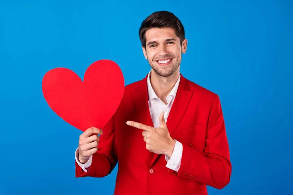 Fotografie mladého muže šťastný pozitivní úsměv ukazováček srdce postava romantické rady volba inzerce izolované přes modré barvy pozadí — Stock fotografie