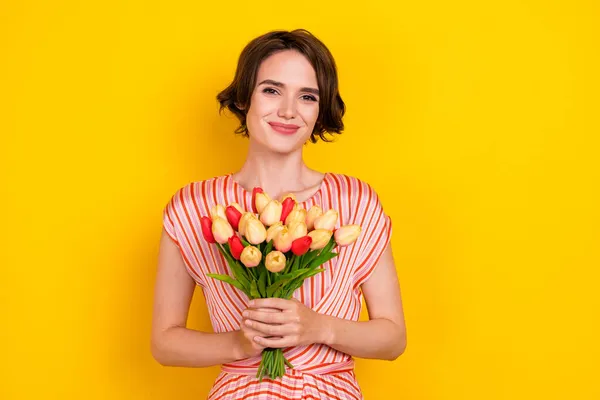 Πορτρέτο της ελκυστικό χαρούμενο κορίτσι ανθοπώλης κρατώντας στα χέρια φρέσκα λουλούδια απομονώνονται σε φωτεινό κίτρινο χρώμα φόντο — Φωτογραφία Αρχείου