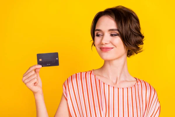 Retrato de menina alegre atraente segurando na mão cartão bancário gastar conta de desconto fundo isolado sobre fundo de cor amarelo brilhante — Fotografia de Stock