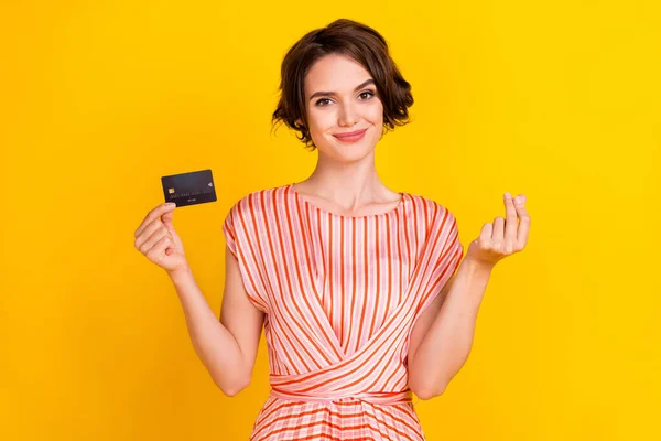 Porträtt av attraktiv glad flicka innehav i handen bankkort visar ge mig kontanter tecken isolerad över ljusgul färg bakgrund — Stockfoto