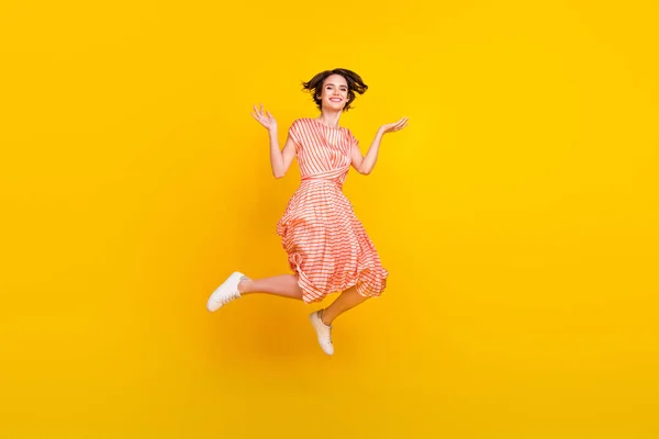 Fénykép az izgatott energikus lány ugrás fel karok kopás csíkos ruha cipők elszigetelt sárga szín háttér — Stock Fotó