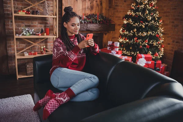 Foto av glad dam sitta soffa hålla telefon läsa grattis sms bära pullover i dekorerade hem inomhus — Stockfoto