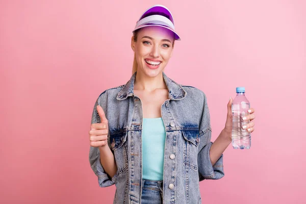 Photo of adorable cute young woman dressed denim jacket smiling drinking water showing thumb up isolated pink color background — Stock Photo, Image