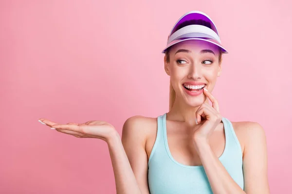 Photo of funny blond young lady hold look empty space wear blue top visor isolated on pink color background — Stock Photo, Image