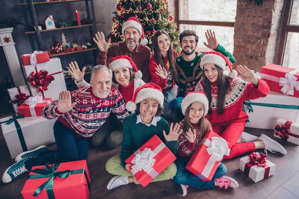 Портрет привлекательной веселой семьи, держащей в руках подарочные коробки, машущие приветствиями накануне рождественской вечеринки дома — стоковое фото