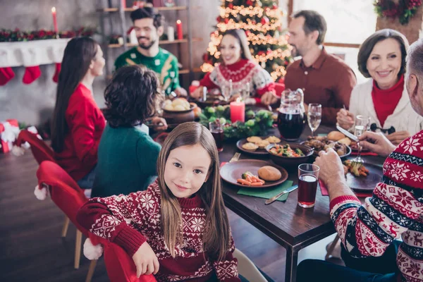 Фотопортрет маленької дівчинки в светрі, що святкує зимові канікули з сім'єю, сидячи за столом на новий рік — стокове фото