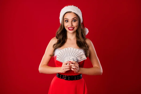 Фото молодої чарівної дівчини щаслива посмішка тримає гроші долари сезон покупки одягу Санта-капсула ізольовані на фоні червоного кольору — стокове фото