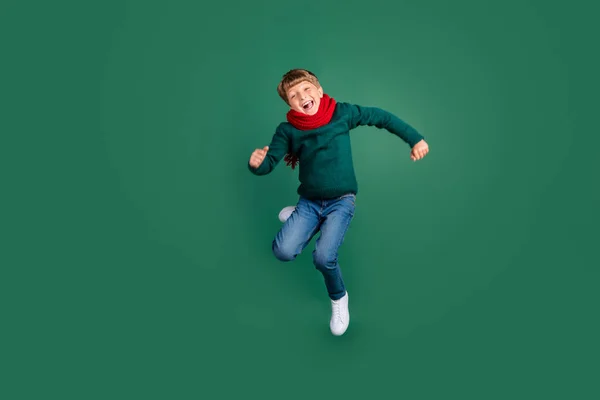 Yeşil süveter giymiş tatlı bir okul çocuğunun fotoğrafı yüksekten atlayan yeşil renkli bir arka plan. — Stok fotoğraf