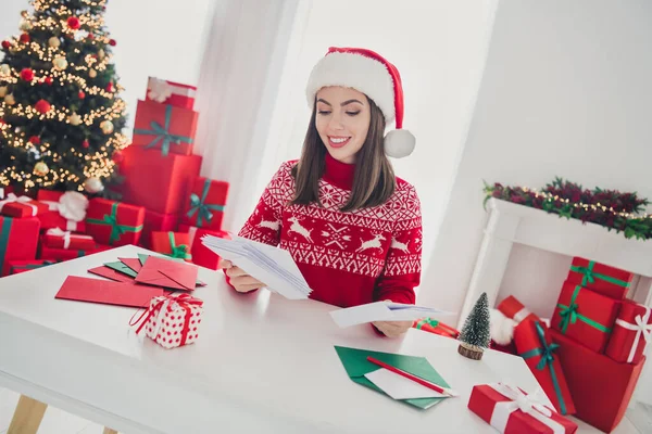 Pozitif bir bayanın fotoğrafı bir sürü zarf alır Noel Baba şapkası takar kapalı bir evde Noel Baba 'nın evine çekilir. — Stok fotoğraf