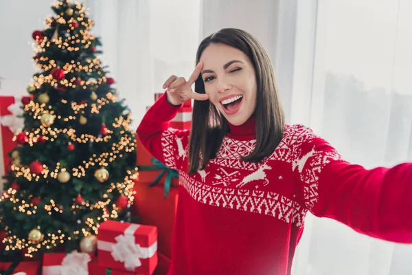 Фото молодой веселой девушки блоггер сделать селфи дурачить шоу мира V-символ декора рождественской елки в помещении — стоковое фото