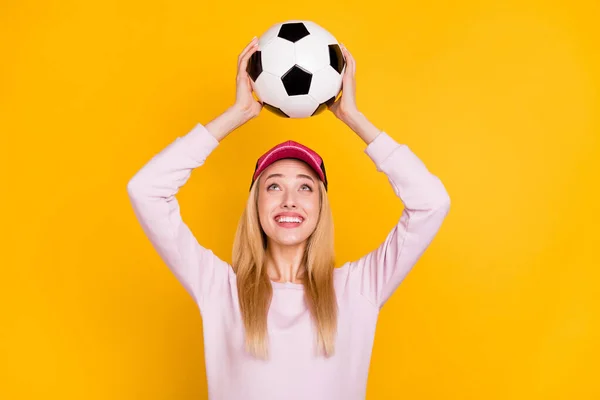 Foto de doce encantador jovem senhora desgaste rosa camisola headwear sorrindo jogando olhando bola isolado cor amarela fundo — Fotografia de Stock