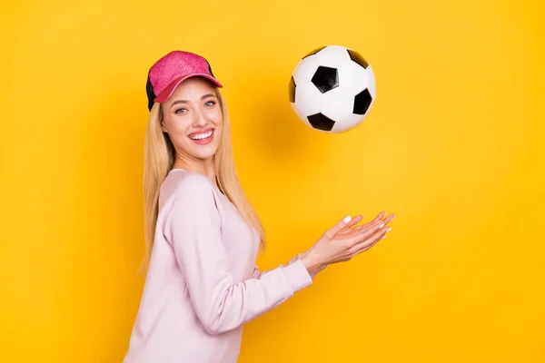 Foto di adorabile brillante giovane donna vestita rosa pullover copricapo cattura palla sorridente isolato colore giallo sfondo — Foto Stock