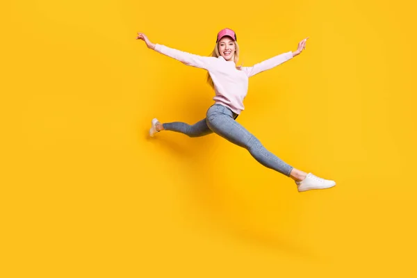 Foto de despreocupado brillante joven dama usar suéter rosa headwear sonriendo saltando alto aislado color amarillo fondo —  Fotos de Stock