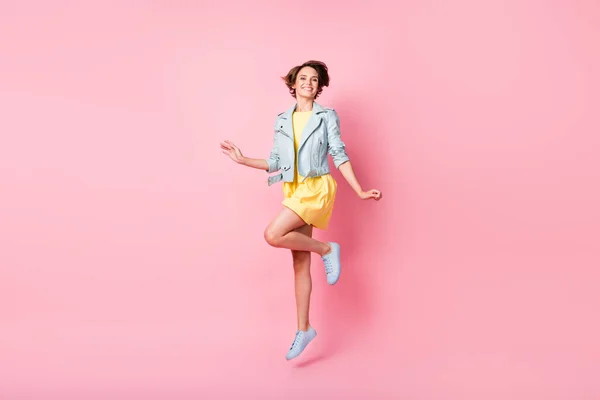 Foto de senhora desportiva saltar radiante sorriso brilhante desgaste amarelo vestido curto calçado isolado cor rosa fundo — Fotografia de Stock