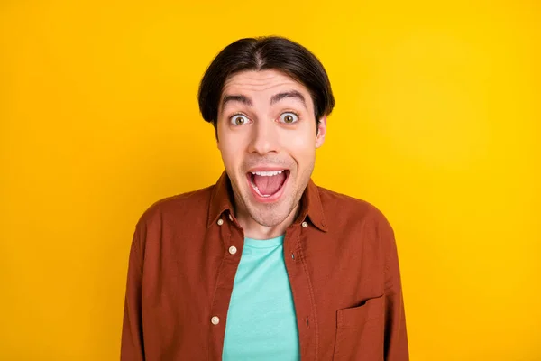Foto van grappige onder de indruk jongeman dragen bruin shirt open mond geïsoleerde gele kleur achtergrond — Stockfoto