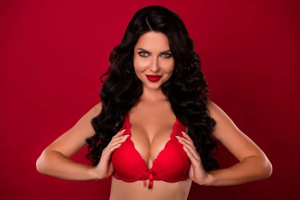 Retrato de atractivo vampiro desnuda glamorosa chica de pelo ondulado tocando sujetador de encaje de gran tamaño aislado sobre fondo de color rojo brillante — Foto de Stock