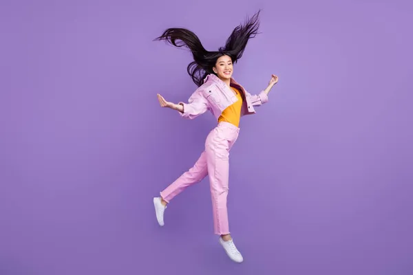 Full length profile photo of nice young brunette lady jump wear jacket jeans sneakers isolated on violet background — Stock Photo, Image