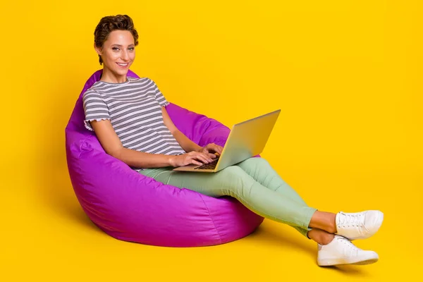 Foto profil lengkap ceo wanita muda duduk di tas laptop kerja memakai sepatu jeans t-shirt terisolasi di latar belakang kuning — Stok Foto