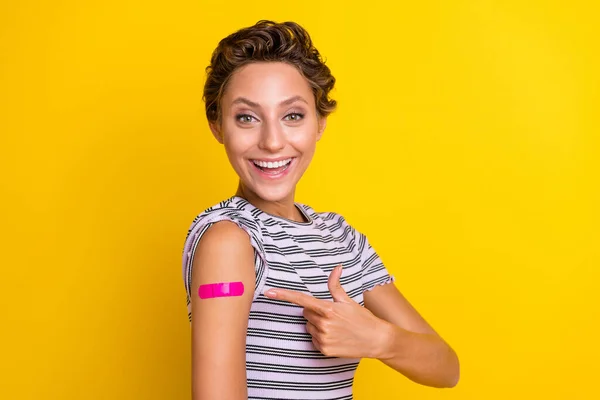 Foto do hooray jovem penteado marrom senhora ponto braço vacinado desgaste branco t-shirt isolada no fundo amarelo — Fotografia de Stock