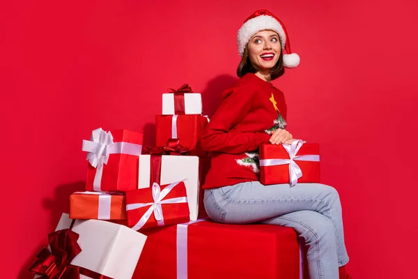 Foto de mujer de ensueño brillante usar suéter adorno sentado celebración de regalos de año nuevo buscando espacio vacío aislado color rojo fondo — Foto de Stock