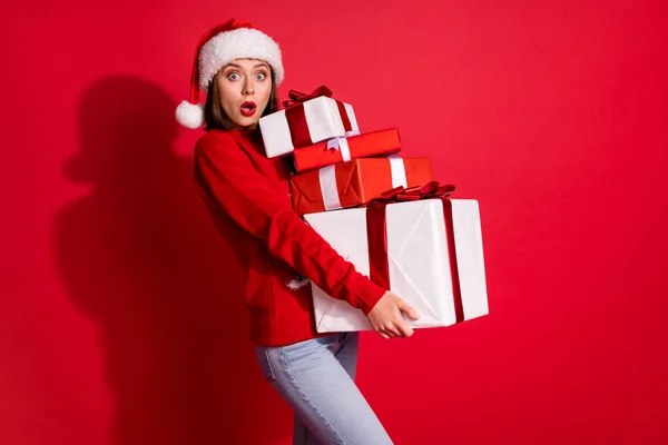 Fénykép funky lenyűgözött fiatal nő viselni dísz pulóver szállító Noel ajándékok séta elszigetelt piros szín háttér — Stock Fotó