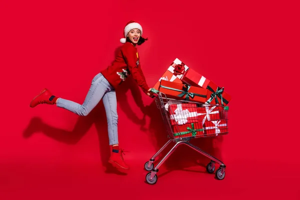 Photo de brillant funky jeune dame habillé pull imprimé souriant marchant acheter noel présente isolé fond de couleur rouge — Photo