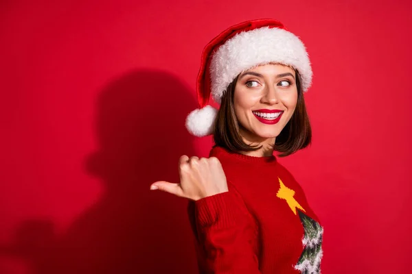 Фото мрійливої солодка молода жінка носить прикрашений светр, насолоджуючись Різдвом, вказуючи назад порожній простір ізольований червоний колір фону — стокове фото