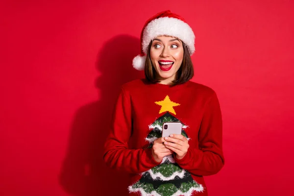 Photo of adorable excited lady dressed pullover celebrating new year chatting gadget looking empty space isolated red color background — Stock Photo, Image