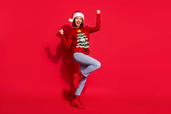 Φωτογραφία του τυχερού αστεία νεαρή γυναίκα φορούν εκτύπωση πουλόβερ αυξάνεται γροθιές γιορτάζει το νέο έτος απομονωμένο φόντο κόκκινο χρώμα — Φωτογραφία Αρχείου