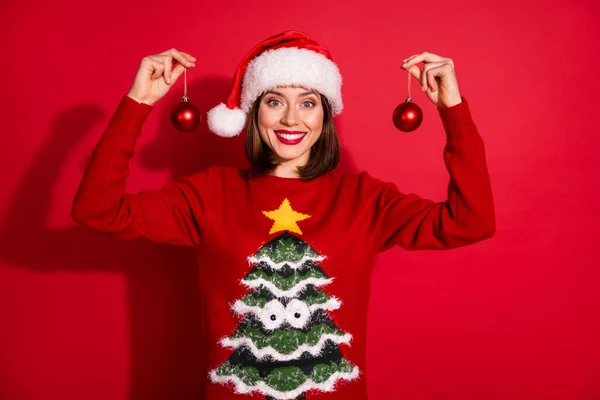 Фото милої чарівної молодої жінки в костюмі, що тримає різдвяні прикраси ізольований червоний колір фону — стокове фото