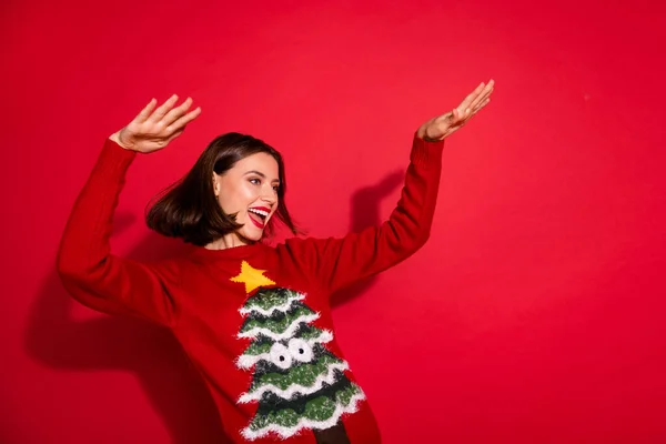 Foto de encantador funky jovem senhora vestido pulôver impressão sorrindo dança celebrando noel isolado fundo cor vermelha — Fotografia de Stock