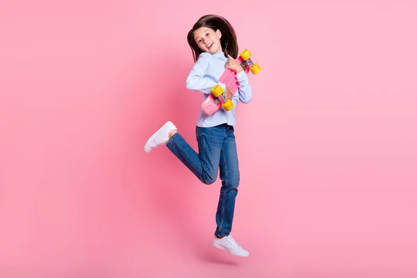 Vista completa del tamaño del cuerpo de la chica bastante alegre saltando sosteniendo el baile del patín divirtiéndose aislada sobre el fondo de color rosa — Foto de Stock