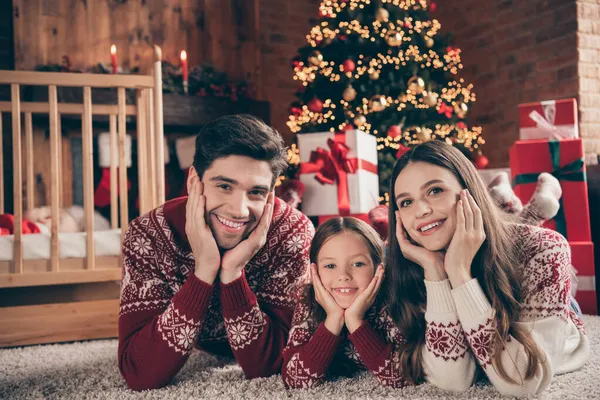 Foto van vrolijke mensen leggen vloer palmen wangen ontspannen noel wonder dragen trui in ingerichte flat binnen — Stockfoto