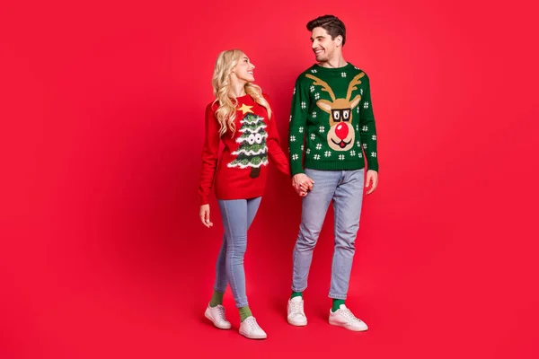 Photo of lover couple hold hands enjoy promenade wear ugly ornament sweater isolated red color background — Stock Photo, Image