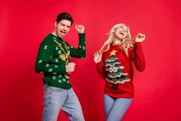 Фотопортрет смеющаяся пара в свитерах танцующая на рождественской вечеринке в праздничные дни изолированный ярко-красный цвет фона — стоковое фото