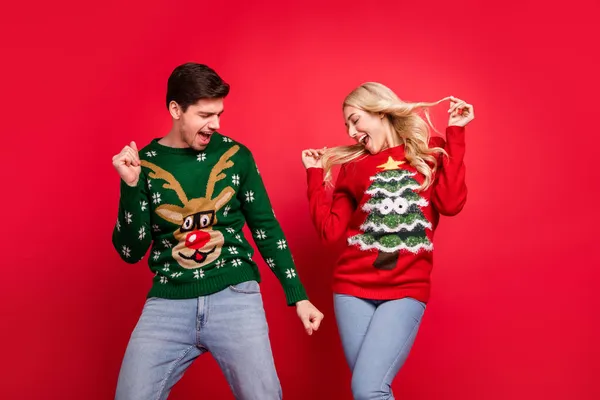 Foto van schattig charmant jong paar gekleed lelijke print truien glimlachen dansen geïsoleerde rode kleur achtergrond — Stockfoto