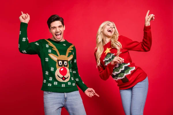 Foto retrato riendo pareja usando suéteres bailando en fiesta de Navidad aislado vívido color rojo fondo —  Fotos de Stock