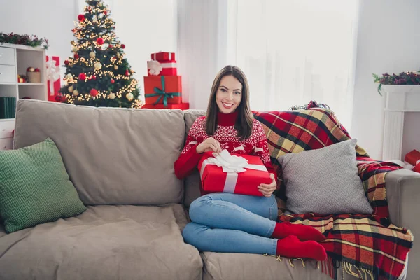 Fotografie veselý sen milá dáma sedět pohodlné pohovka rozbalit dárek oblečení svetr v dekorované x-mas doma uvnitř — Stock fotografie