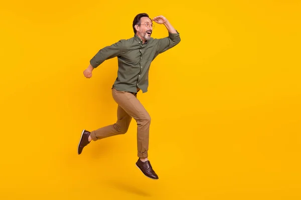Повна довжина вигляду тіла привабливого враженого чоловіка, що стрибає, виглядає далеко ізольованим на яскраво-жовтому кольоровому фоні — стокове фото