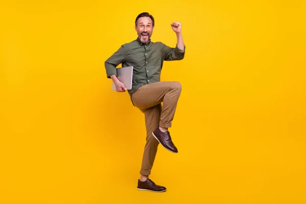 Full size photo of mature man happy positive smile rejoice victory hold laptop isolated over yellow color background — Stock Photo, Image