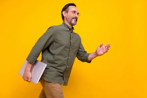 Profil côté photo de mature homme heureux sourire positif tenir ordinateur portable aller réunion isolé sur fond de couleur jaune — Photo