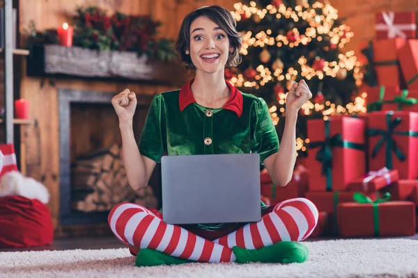 Foto von glänzenden glücklichen jungen Dame tragen Elfenkleidung Eingabe moderner Gerät feiert Weihnachten erhobenen Fäusten lächelnd drinnen Haus Home Room — Stockfoto