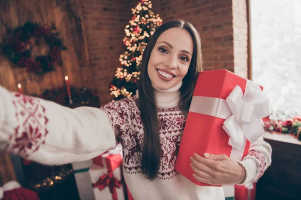 Foto de divertida linda mujer madura usar suéter de impresión sonriente viraje selfie celebración de regalo de año nuevo en el interior casa casa habitación — Foto de Stock